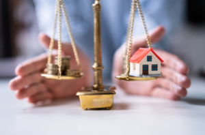 man showing a scale holding a house on one side and money on the other to represent dividing assets.