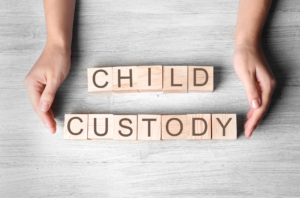 Wooden blocks spelling out "child custody" and hands surrounding them.