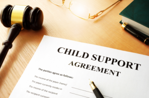 child support agreement paper surround by a gavel, glasses, book, and pen.