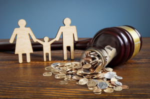 Wooden family representing adoption with coins spilling out of a gavel.