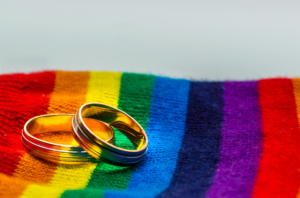 rainbow blanket with wedding rings on it representing same-sex divorce.