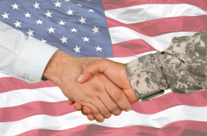 Military hand shaking attorney hand. American flag in background.