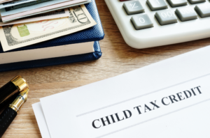 child tax credit document on table with money, book, pen, and calculator.