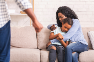 Mother and child on the couch afraid. Fathers fist pointed towards them representing domestic violence.