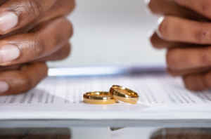 A couple with hands on divorce papers and rings in the middle representing a 90-day separation period before divorce.