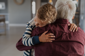 Grandpa hugging grandson, comforting him.